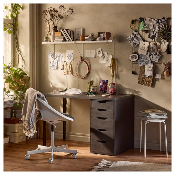 Cosy home office with LAGKAPTEN desk in dark wood, white chair, and decorated shelves.
