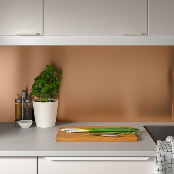 Modern kitchen with LYSEKIL panel. Counter has green onions, knife, plant, and bowl.