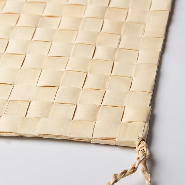 Handcrafted woven palm leaf placemat, natural beige, neatly braided edge.