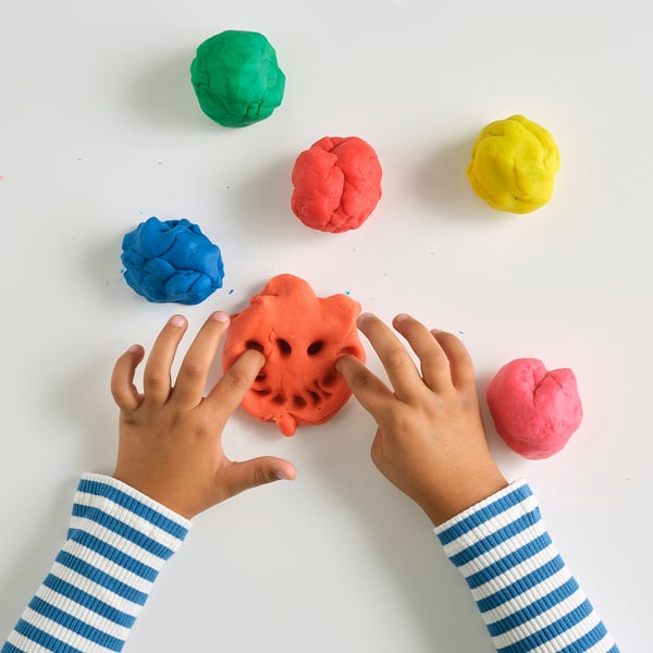 Kids playing with multicoloured modelling clay.