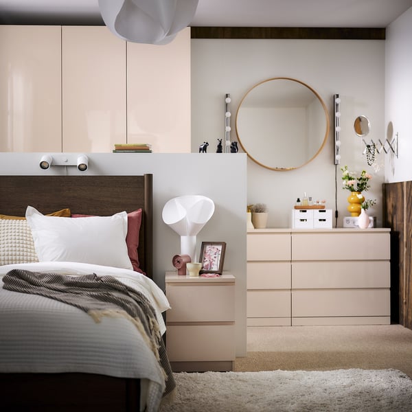 Modern bedroom with MALM light orange chest & dresser, wooden headboard, white rug, decorative items, and round mirror.