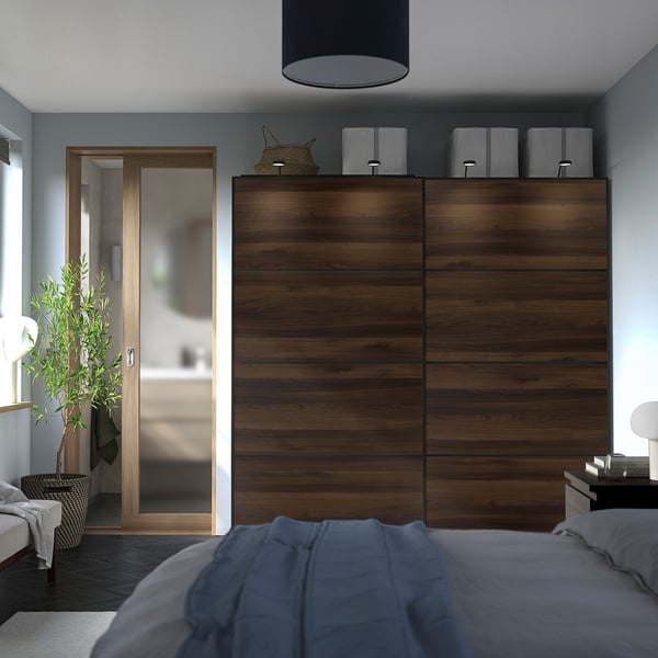 Minimalist bedroom with large wooden pax closet, blue bedding, and a potted plant.