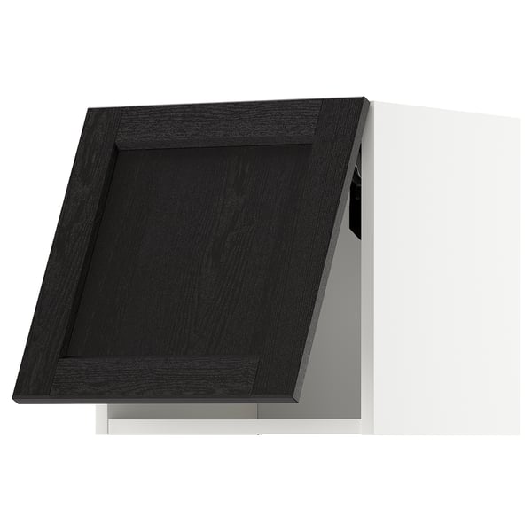 Black kitchen cabinet with a traditional design, made of stained wood. A single door with bevelled edges, set against a white wall.
