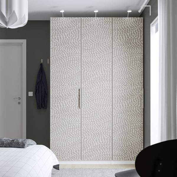 A large white wavy-patterned MISTUDDEN wardrobe, towering over a bed and chair, with its size dominating the room.