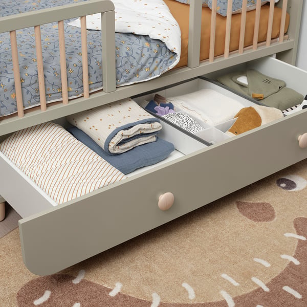 Childrens cot with adjustable, removable side and under-bed drawer for storage.