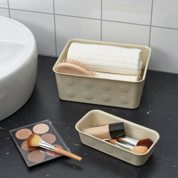 Bathroom counter with black marble, beige organiser holding towels and brushes, and makeup items.