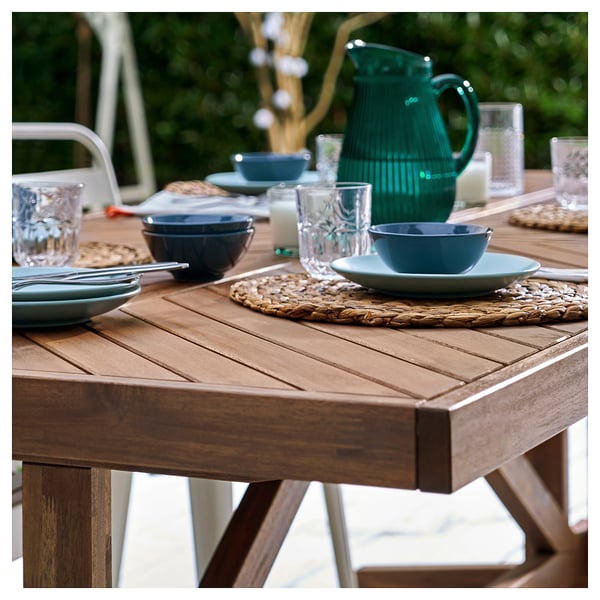 Outdoor picnic table with plates and bowls. Handcrafted acacia wood, natural grain.