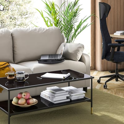 Modern living space with grey sofa, black laptop tray, green rug, and wooden floor.