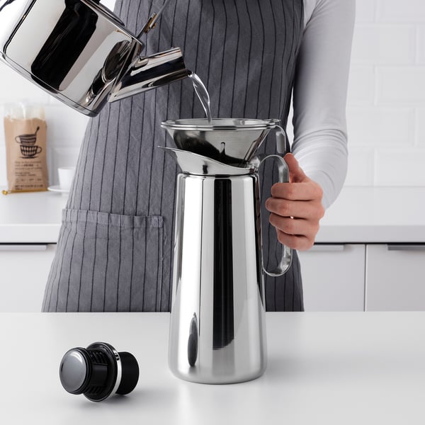 Pouring water into a sleek, modern coffee maker with reusable philtre on countertop.
