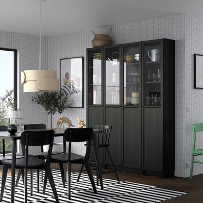 Black OXBERG bookcase with glass doors in modern dining room, displaying dishes and a picture.