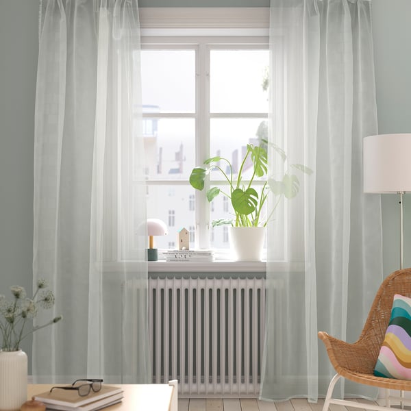 Room with long sheer curtains, green plant, soft light or, for a closer count: bright room with long white curtains, plant, soft light