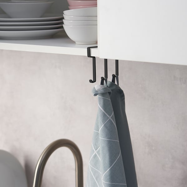 A hook rack attached under a white cabinet holds a light blue tea towel. It efficiently uses space for storage.
