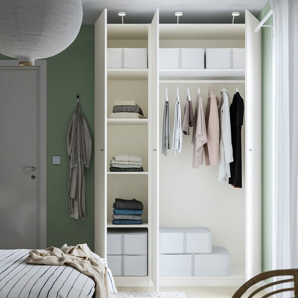 A modern closet, PAX, displaying clothes and folded items on shelves, with adjustable feet and integrated lighting.