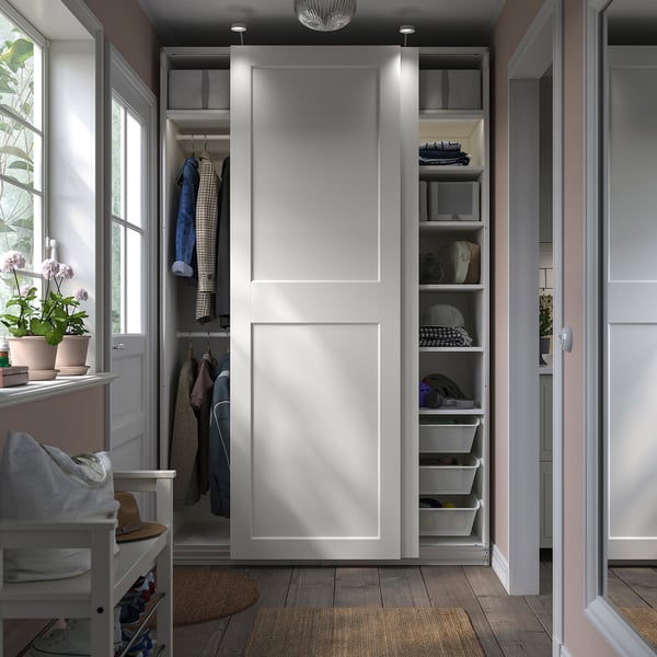 Modern white wardrobe with sliding doors, shelves, and hanging space. Includes a chair, plants, and wooden floor.