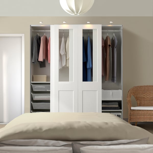 White PAX wardrobe with glass & wood panels, tall & filled with clothes.
