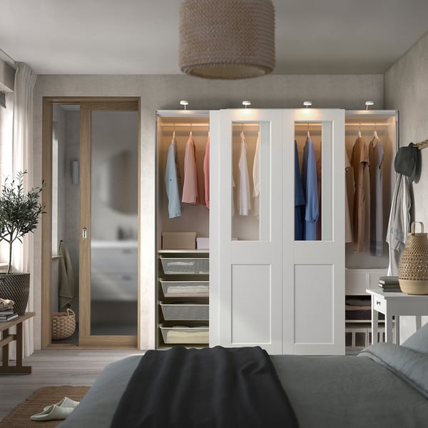 Modern bedroom with white PAX wardrobe, neat clothes, cosy bed.