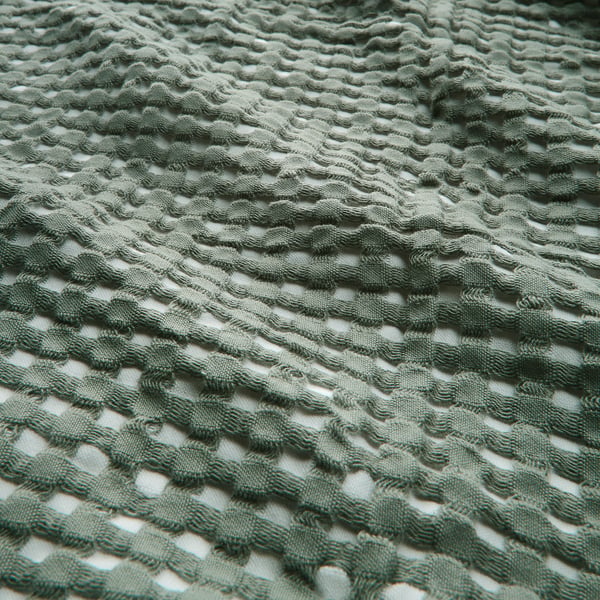 Soft, textured green cotton blanket with waffle weave pattern, reversible design.