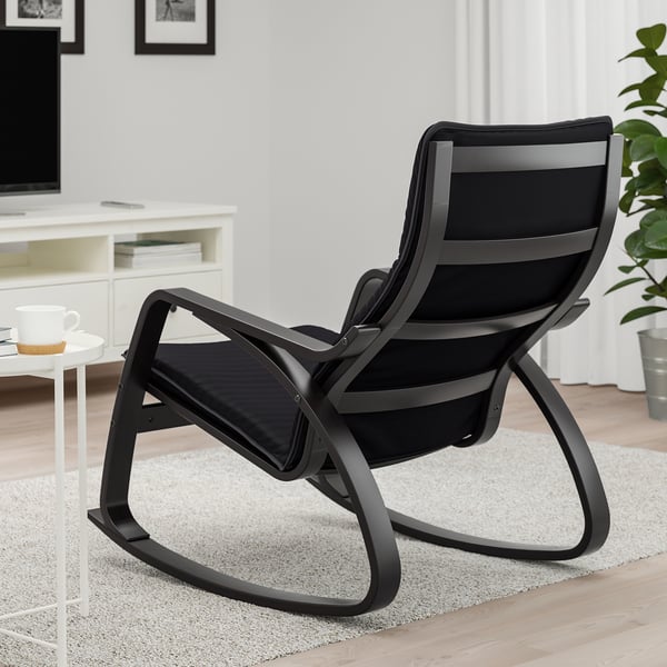 Black rocking chair with high back and curved arms, ideal for relaxing. Positioned on a light-colored rug in a cosy living space.