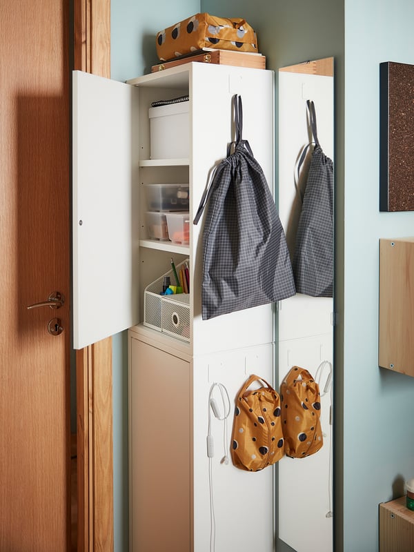White cabinet with shelves, storage boxes, grey & orange RENSARE bags, blue wall.