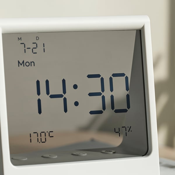 A modern digital clock displaying 14:30, with date, temperature, and humidity, set on a sleek, white, and minimalist design.