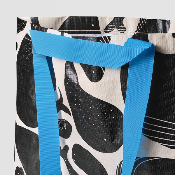 Reusable shopping bag with abstract black and white patterns. Handles are sturdy and blue, showcasing quality recycled materials.