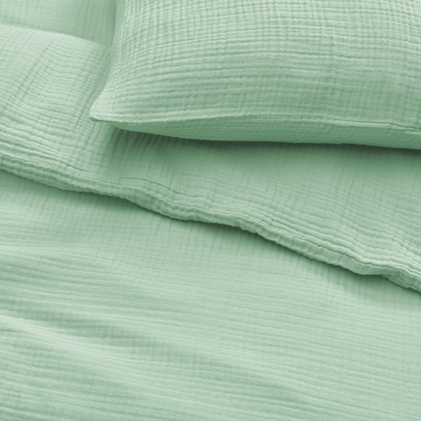 Soft, folded mint green bed sheets, neatly arranged. Texture suggests high-quality, breathable cotton.