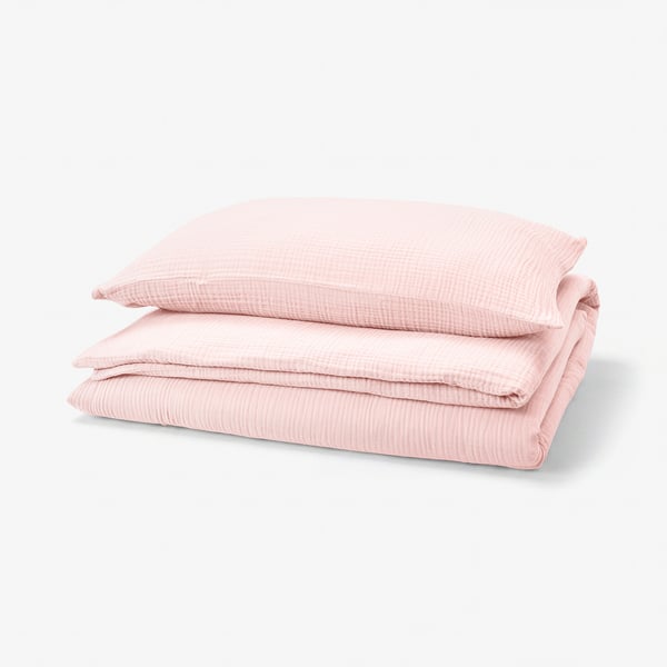 Folded pink SCHERSMIN duvet set of organic cotton, neatly stacked with textured surface and envelope/enclosure designs.