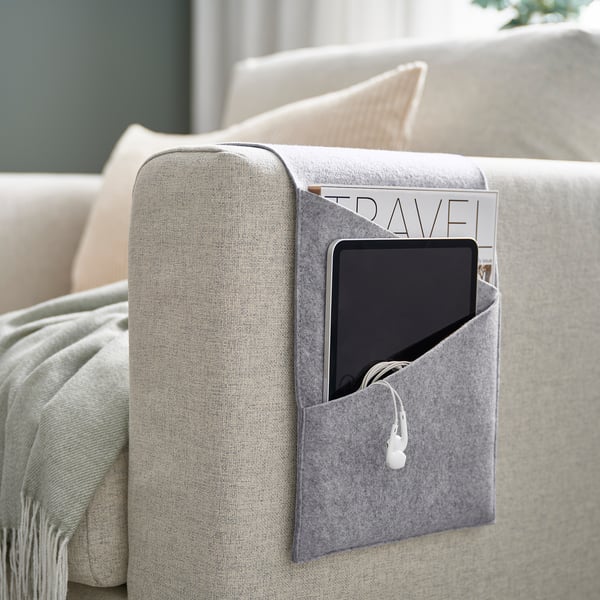Grey felt storage pocket hangs on sofa arm, holding a tablet and magazine, keeping items organised.