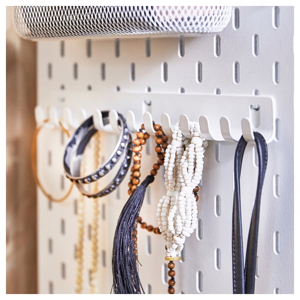 SKÅDIS white pegboard with jewellery holding hooks, displaying bracelets, beads, and chains. Organised and neat.