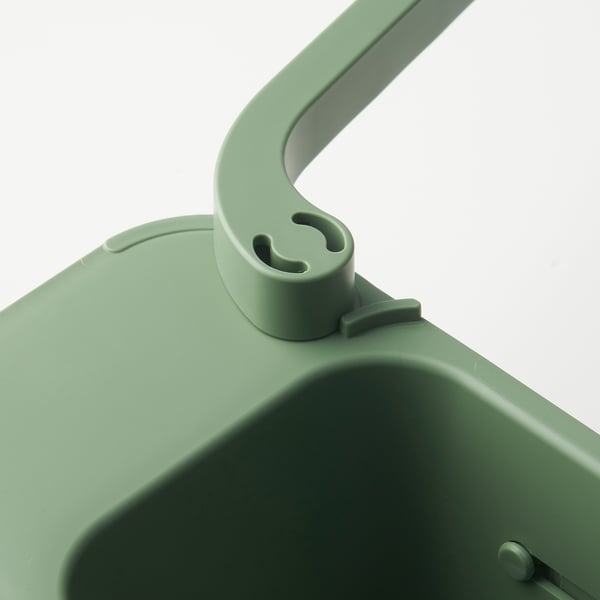 Close-up of SKOLÄST green sink organisers sturdy handle and base with drainage holes.