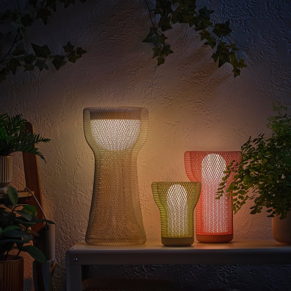 Three decorative lights on a shelf, lit with plants.
