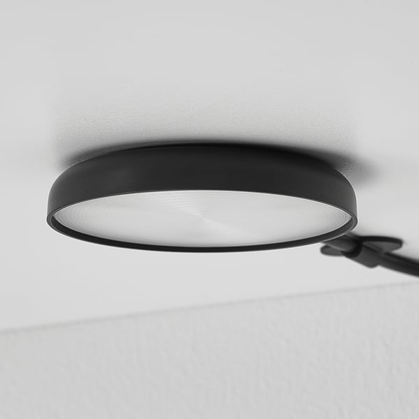 Modern ceiling-mounted black spotlight emitting bright, diffused light.