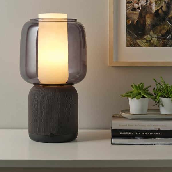 A wifi speaker lamp with a black speaker base and a glass shade. Its equipped with 180-degree sound and controlled via the sonos app.