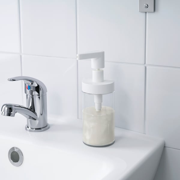 Modern bathroom sink with chrome tap and clear soap dispenser filled with liquid soap.