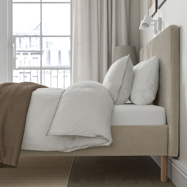 Bed frame with padded headboard, loose-fitting cover, and hanging skirt, ideal for easy cleaning and comfort.