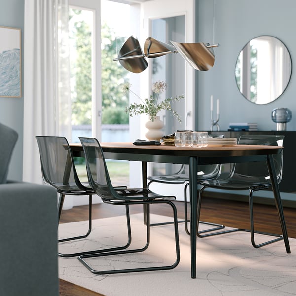 Modern dining room with rectangular walnut table, black metal chairs, pendant lamp, and mirror.