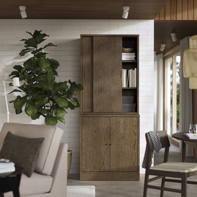 Honeycomb particleboard cabinet, oak veneer, 2 doors, shelves. White brick wall, chair, plant, spotlights.
