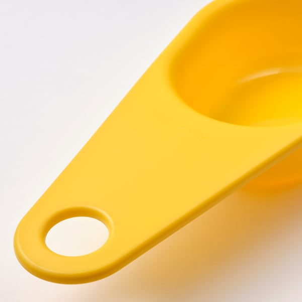 Bright yellow measuring cup, made of smooth polypropylene plastic, designed for precise measurements and easy stacking.