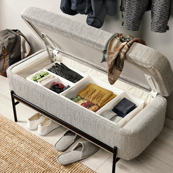 Organised storage bench with open lid revealing divided compartments filled with accessories. Hinged lid supported by gas spring for easy access.