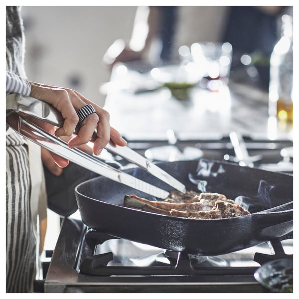 Cooking steak in a VARDAGEN black cast iron pan on a gas stove.