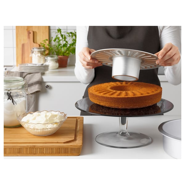 Person places cake pan on stand, removable base for easy removal.