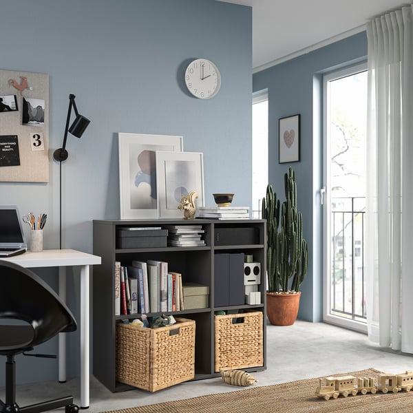 Modern blue home office with VIHALS dark grey storage unit, white desk, black chair, wall clock, and large window with white curtains.