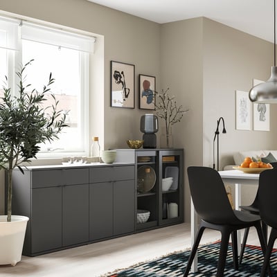 Modern dining room with grey cabinet and black chairs, colourful rug, and wall art.