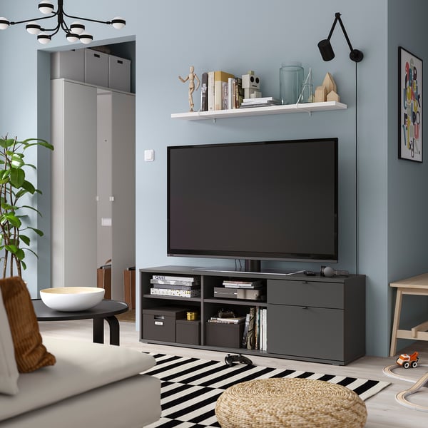 Modern living room with VIHALS tv bench, flat-screen tv, striped rug, white sofa, and wall sconce. Minimalist style.