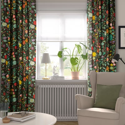 Cosy living room with dark floral curtains, green armchair, and a window sill with a lamp, books, and plant.