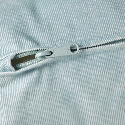 Close-up of light blue zip on soft, ribbed fabric. High-quality feel, smooth slider, durable construction.