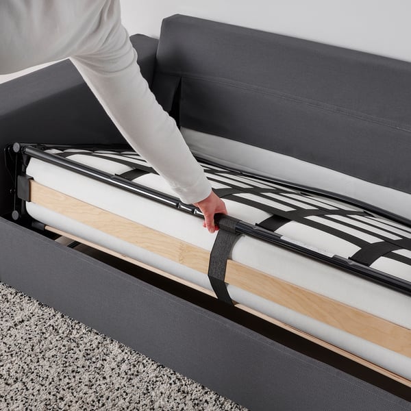 Person pulls out sofa-bed with thick mattress. Easy to convert and comfortable for sleeping.
