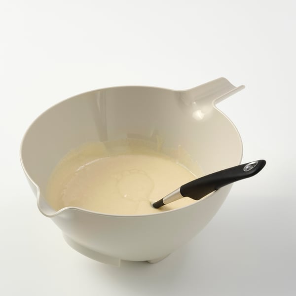 White bowl with spoon-handle spout on white surface