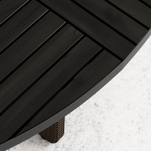 Dark wooden round outdoor table with a woven wicker leg on snow.