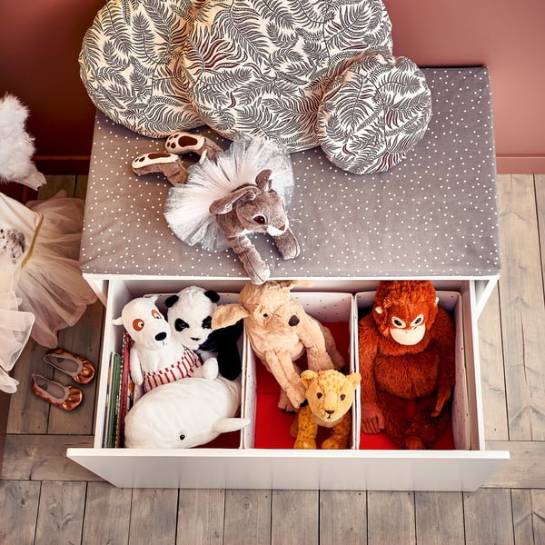 White polka dot ottoman filled with stuffed animals.